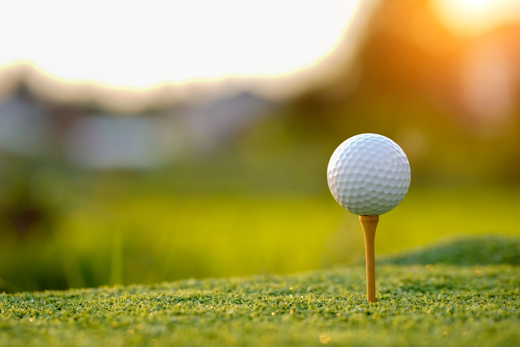 Golf ball on tee in the evening golf course with sunshine background